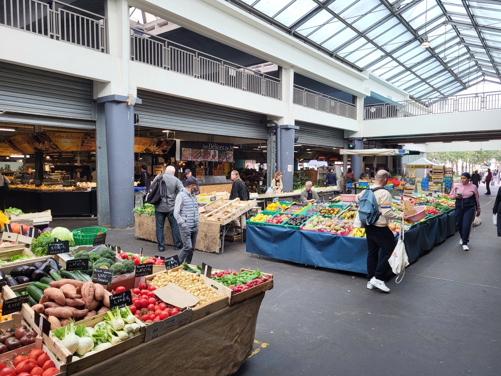 Interior del Marché des Capucins de Burdeos, con sus puestos de verduras y frutas y su techo de cristal